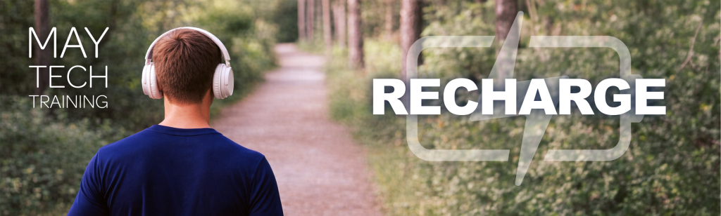 Back view of a person wearing white headphones walking on a wooded path; overlay text reads “May Tech Training” and “Recharge” with a battery symbol.